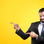 Businessman pointing to the side over yellow background