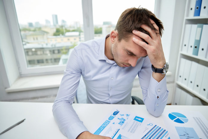 stressed businessman with papers in office