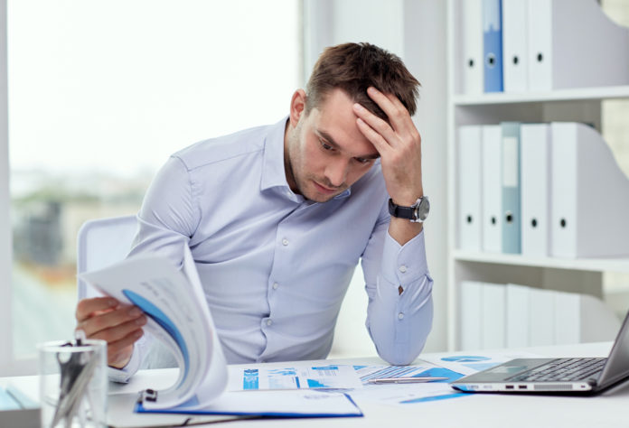 stressed businessman with papers at office